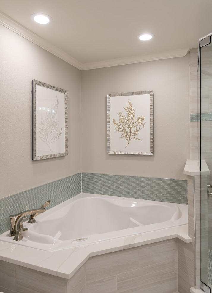 Photo of a large transitional master bathroom in Dallas with white cabinets, a corner tub, a corner shower, a one-piece toilet, white tile, glass tile, grey walls, porcelain floors, an undermount sink, engineered quartz benchtops, grey floor, a hinged shower door and raised-panel cabinets.
