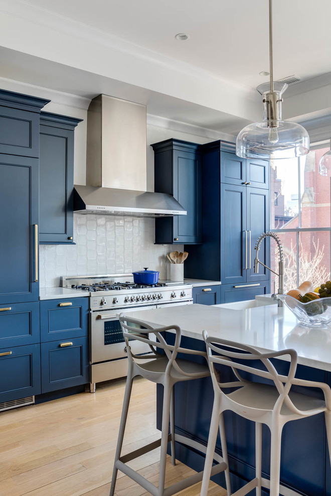 Example of a transitional light wood floor eat-in kitchen design in Boston with blue cabinets, stainless steel appliances, an island and white countertops