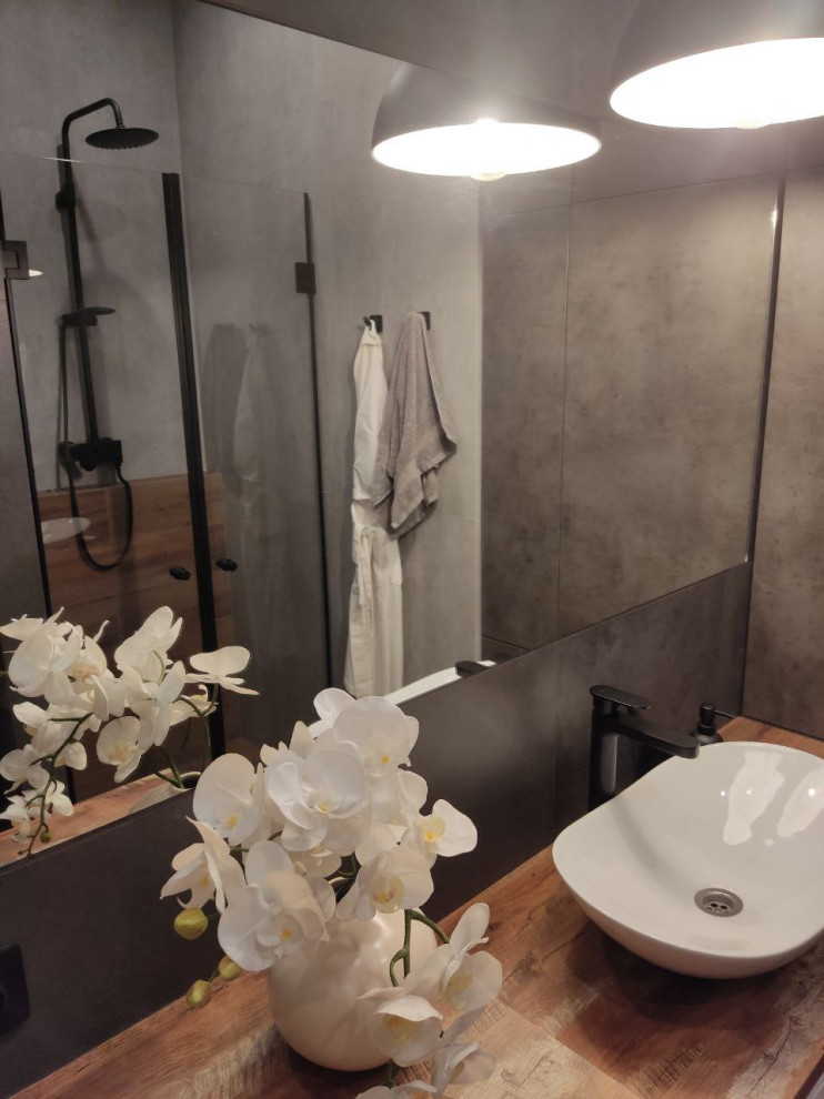Exempel på ett litet modernt brun brunt badrum med dusch, med skåp i mörkt trä, en kantlös dusch, grå kakel, porslinskakel, klinkergolv i porslin, ett nedsänkt handfat, träbänkskiva, brunt golv och dusch med gångjärnsdörr