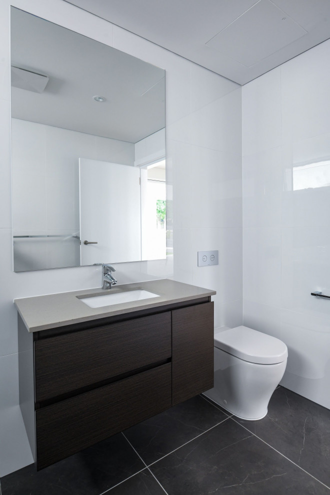 Photo of a mid-sized contemporary 3/4 bathroom in Sydney with beaded inset cabinets, grey cabinets, a one-piece toilet, gray tile, ceramic tile, grey walls, ceramic floors, an undermount sink, engineered quartz benchtops, grey floor, an open shower, brown benchtops, an enclosed toilet, a single vanity and a built-in vanity.