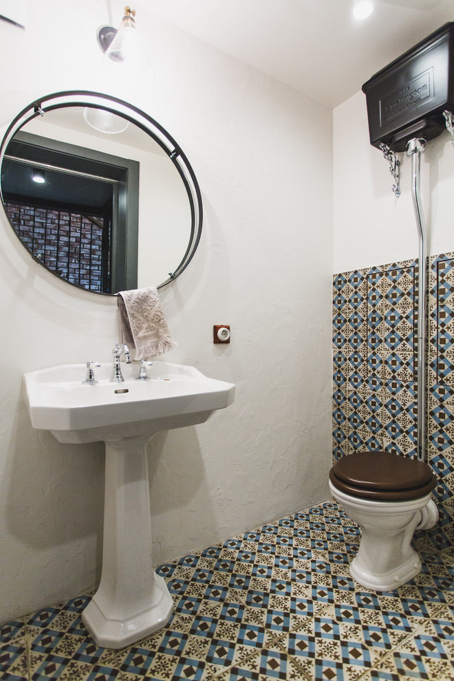 Photo of a mediterranean powder room in Moscow with a two-piece toilet, multi-coloured tile, white walls, a pedestal sink and multi-coloured floor.