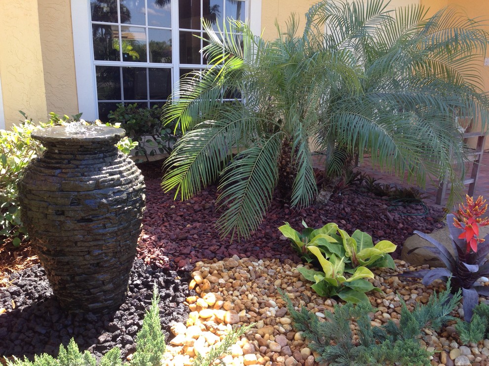 This is an example of a mid-sized traditional front yard partial sun garden in Miami with a water feature and gravel.