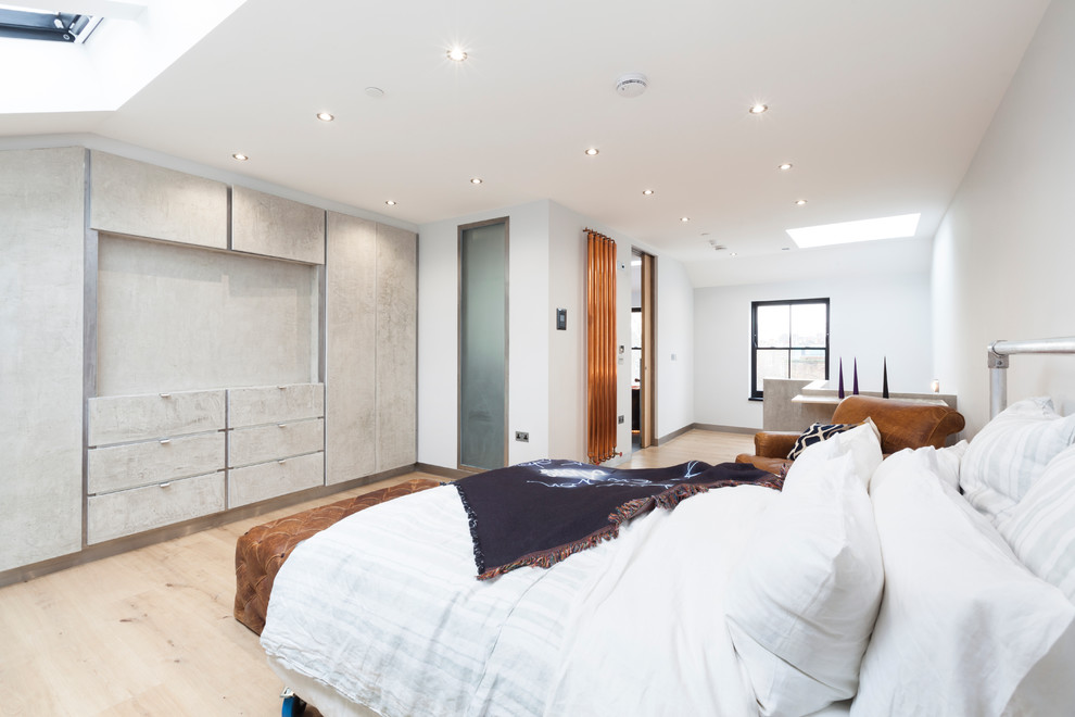 Large traditional loft-style bedroom in London with white walls, light hardwood floors and no fireplace.