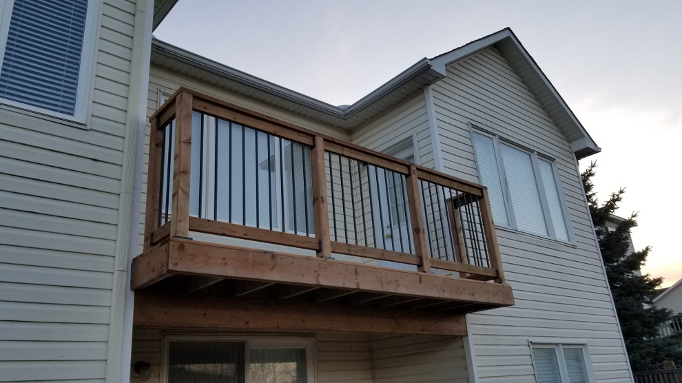 Large modern back ground level metal railing terrace in Ottawa with skirting and no cover.