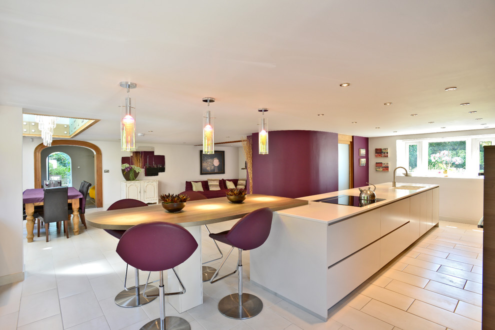 Inspiration for a contemporary galley eat-in kitchen in Manchester with flat-panel cabinets, white cabinets and wood benchtops.