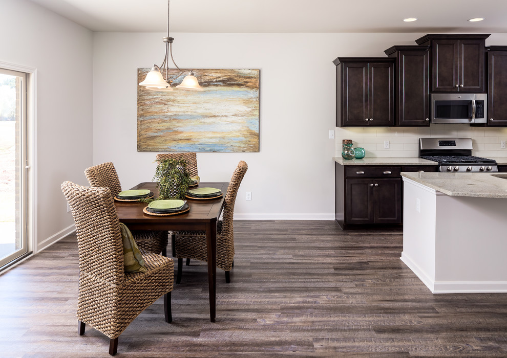 Example of a mid-sized transitional single-wall medium tone wood floor eat-in kitchen design with an undermount sink, shaker cabinets, dark wood cabinets, granite countertops, white backsplash, subway tile backsplash, stainless steel appliances and an island