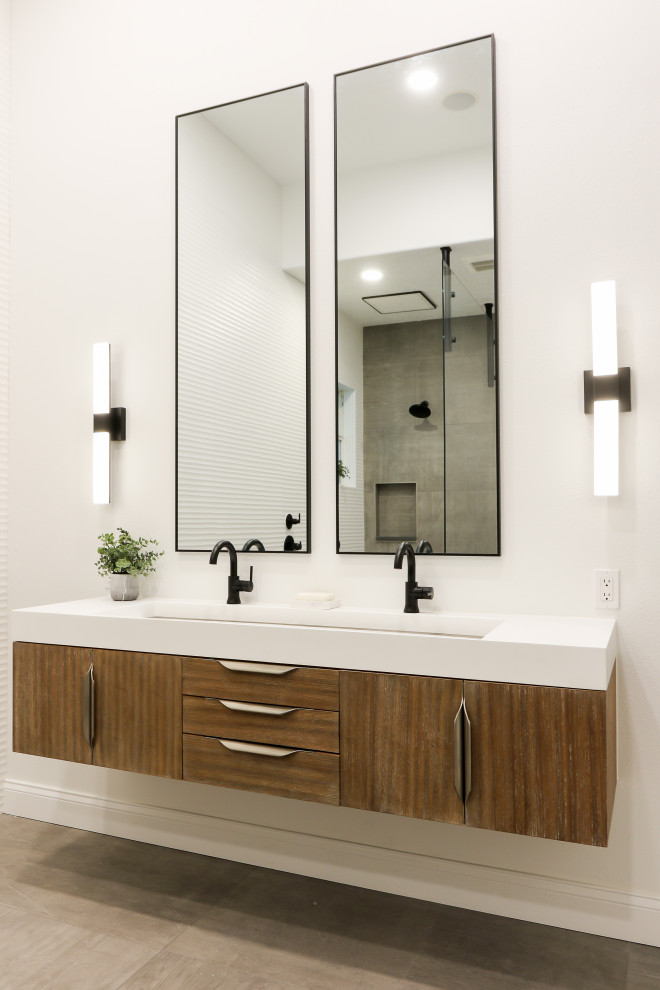 Design ideas for a large modern master bathroom in Orlando with furniture-like cabinets, medium wood cabinets, a freestanding tub, a curbless shower, gray tile, porcelain tile, white walls, porcelain floors, a trough sink, engineered quartz benchtops, grey floor, an open shower, white benchtops, an enclosed toilet, a double vanity and a floating vanity.