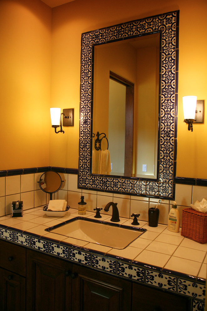 Photo of a mid-sized mediterranean 3/4 bathroom in Sacramento with white tile, ceramic tile, orange walls, a wall-mount sink, tile benchtops, white benchtops, raised-panel cabinets and dark wood cabinets.