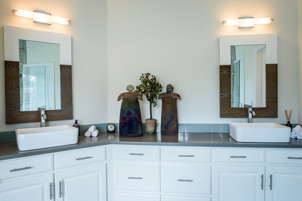 Example of a large transitional master gray tile and glass tile concrete floor drop-in bathtub design in Denver with shaker cabinets, white cabinets, white walls, a vessel sink and quartz countertops