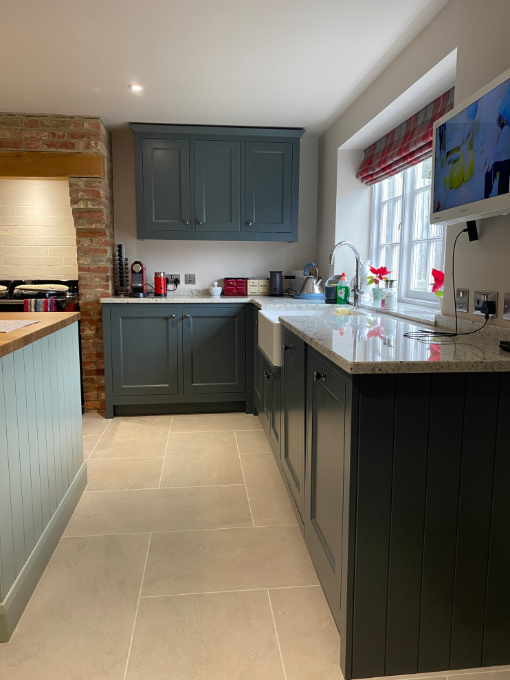 Design ideas for a mid-sized traditional u-shaped eat-in kitchen in Sussex with a farmhouse sink, beaded inset cabinets, grey cabinets, granite benchtops, multi-coloured splashback, granite splashback, panelled appliances, porcelain floors, with island, beige floor and white benchtop.