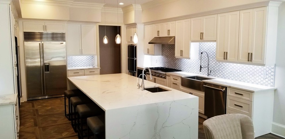 Large transitional u-shaped dark wood floor and brown floor eat-in kitchen photo in Miami with a farmhouse sink, shaker cabinets, white cabinets, stainless steel appliances, an island, white countertops, marble countertops and gray backsplash
