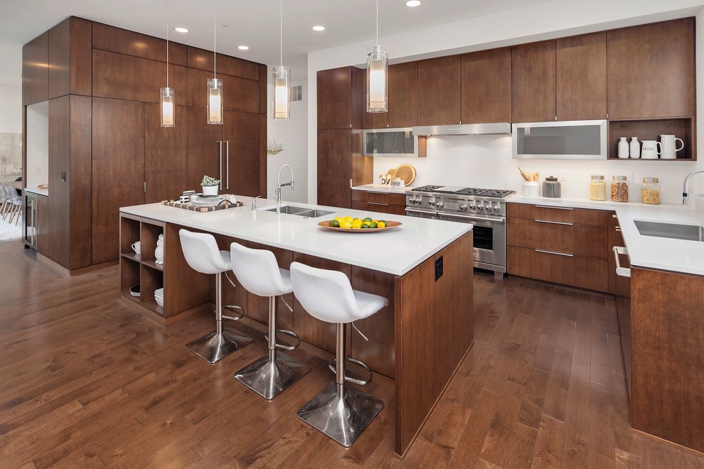 Contemporary u-shaped open plan kitchen in Seattle with an undermount sink, flat-panel cabinets, dark wood cabinets, white splashback, stainless steel appliances, dark hardwood floors, with island and brown floor.