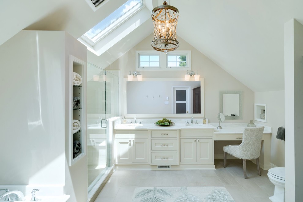 Photo of a large transitional master bathroom in Philadelphia with recessed-panel cabinets, white cabinets, a drop-in tub, a corner shower, a two-piece toilet, white tile, stone slab, white walls, ceramic floors, an undermount sink, quartzite benchtops, white floor and a hinged shower door.