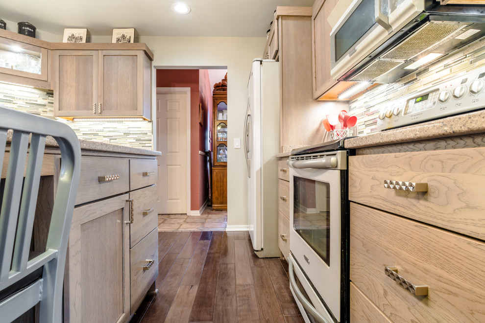 Inspiration for a mid-sized transitional u-shaped medium tone wood floor enclosed kitchen remodel in Miami with a farmhouse sink, shaker cabinets, gray cabinets, quartz countertops, gray backsplash, glass tile backsplash, white appliances and an island