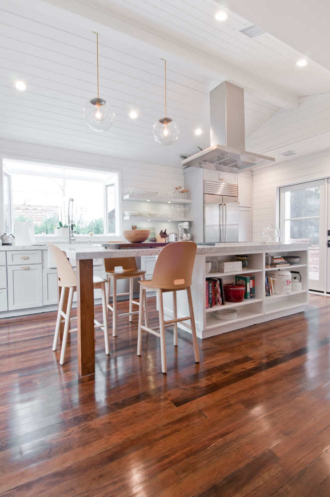 Design ideas for a mid-sized country galley eat-in kitchen in Los Angeles with a farmhouse sink, shaker cabinets, white cabinets, marble benchtops, white splashback, timber splashback, stainless steel appliances, painted wood floors and with island.