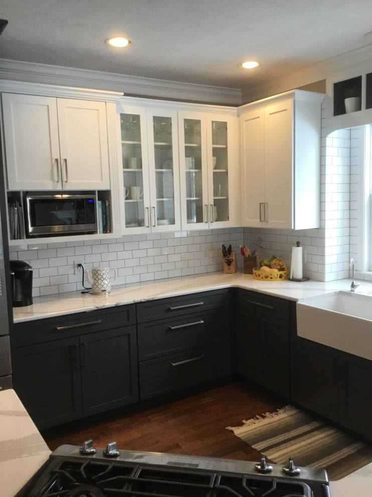 Eat-in kitchen - mid-sized transitional l-shaped dark wood floor and red floor eat-in kitchen idea with a farmhouse sink, recessed-panel cabinets, gray cabinets, stainless steel appliances, an island, white countertops, quartz countertops, white backsplash and subway tile backsplash