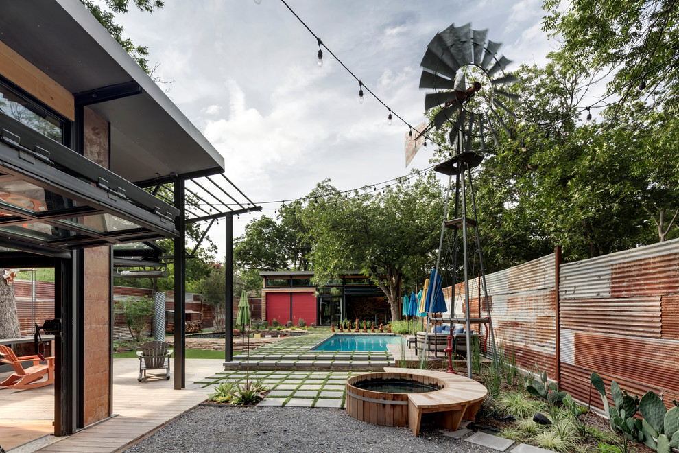 Design ideas for a small industrial backyard patio in Dallas with concrete pavers and a roof extension.