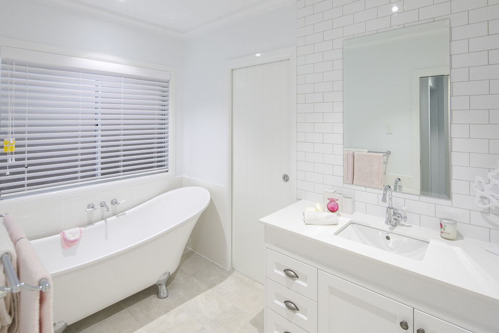This is an example of a large transitional master bathroom in Brisbane with furniture-like cabinets, white cabinets, a claw-foot tub, an open shower, a one-piece toilet, white tile, ceramic tile, white walls, porcelain floors, an undermount sink, quartzite benchtops, beige floor and an open shower.