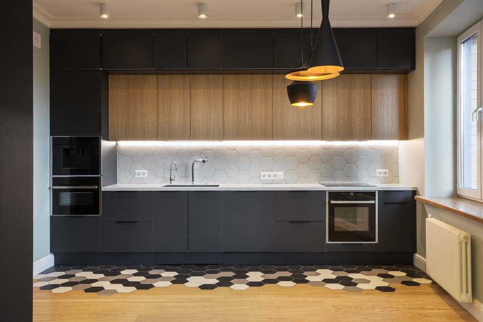 Mid-sized scandinavian single-wall eat-in kitchen in Moscow with an undermount sink, flat-panel cabinets, black cabinets, solid surface benchtops, white splashback, ceramic splashback, black appliances, ceramic floors, no island, white benchtop and multi-coloured floor.