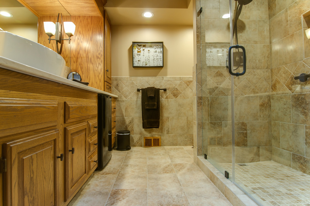 Large transitional master beige tile and ceramic tile ceramic tile and beige floor alcove shower photo with raised-panel cabinets, medium tone wood cabinets, beige walls, a vessel sink, quartz countertops, a two-piece toilet and a hinged shower door