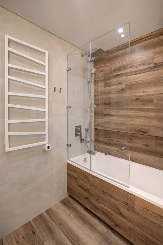 Photo of a mid-sized contemporary master bathroom in Saint Petersburg with flat-panel cabinets, light wood cabinets, an undermount tub, a shower/bathtub combo, a bidet, beige tile, marble, beige walls, wood-look tile, an undermount sink, limestone benchtops, beige floor, a sliding shower screen, white benchtops, a single vanity, a floating vanity and wood walls.