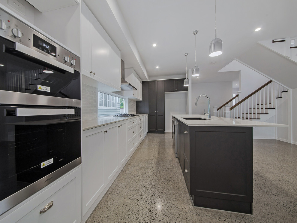 Photo of a mid-sized transitional galley eat-in kitchen in Brisbane with an undermount sink, beaded inset cabinets, white cabinets, marble benchtops, white splashback, ceramic splashback, concrete floors, with island, grey floor and white benchtop.