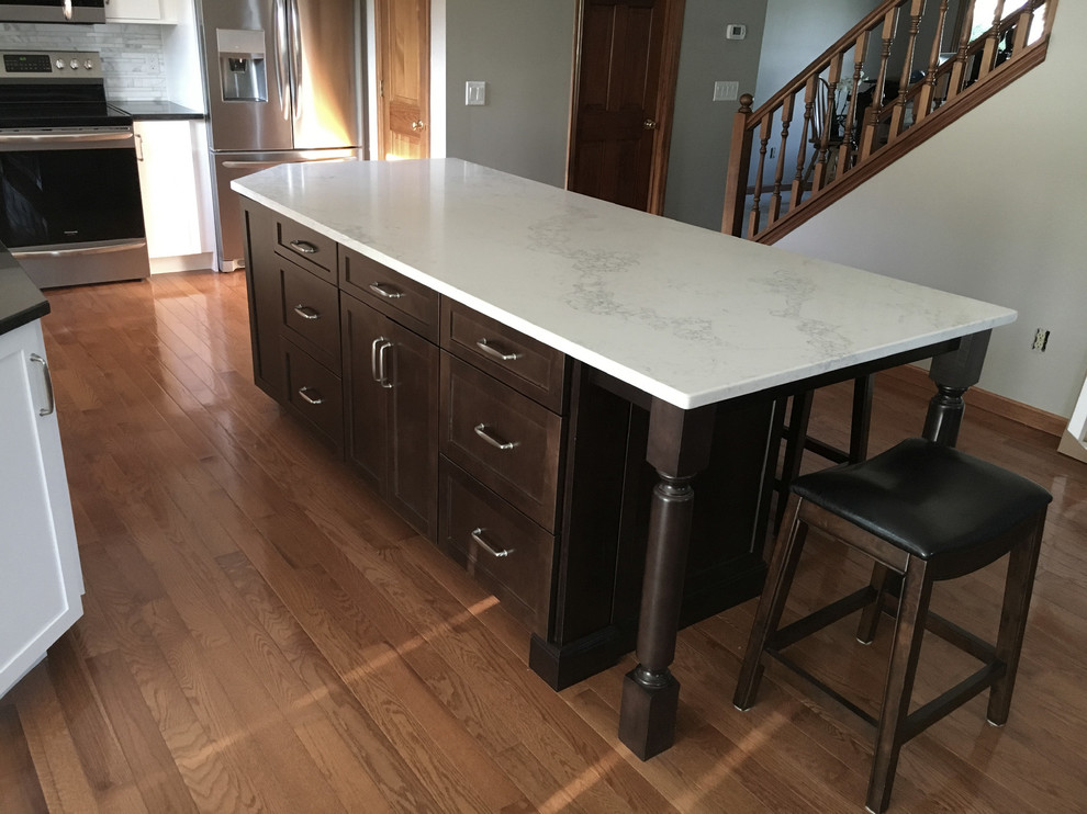 Example of a large transitional single-wall medium tone wood floor eat-in kitchen design with an undermount sink, shaker cabinets, white cabinets, granite countertops, multicolored backsplash, marble backsplash, stainless steel appliances, an island and black countertops