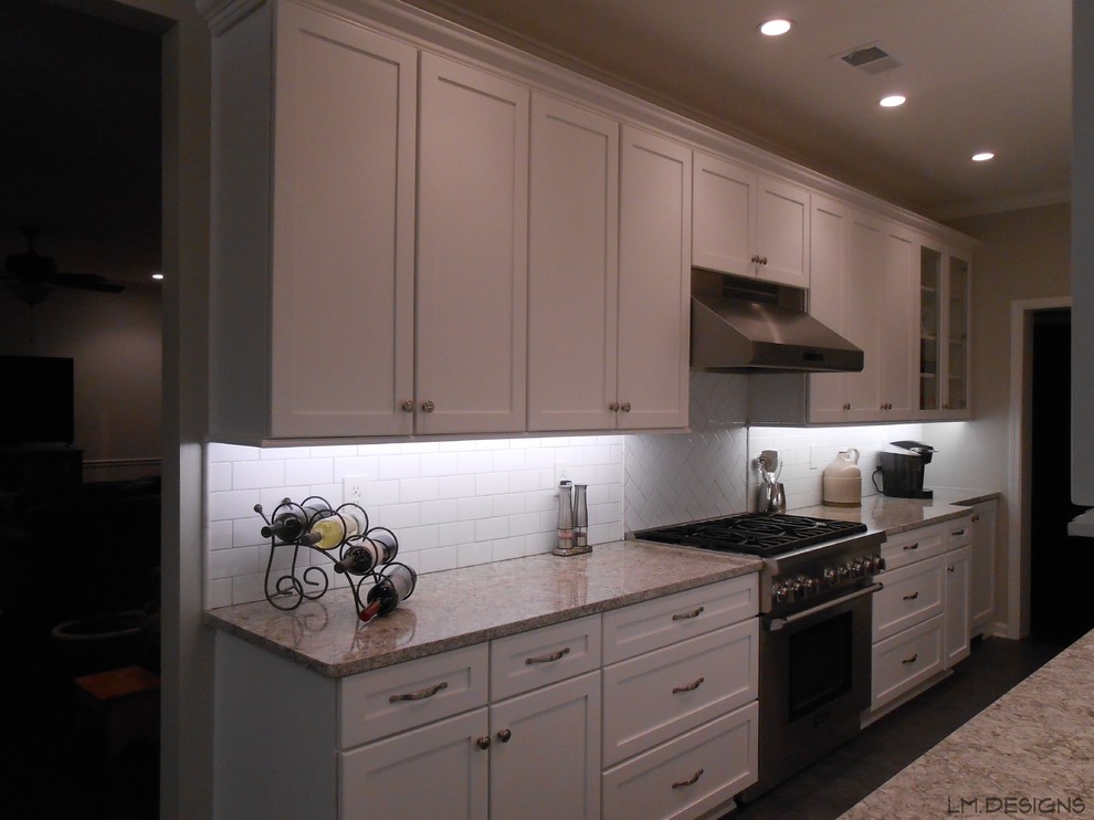 Example of a transitional galley porcelain tile eat-in kitchen design with shaker cabinets, white cabinets, quartz countertops, white backsplash, ceramic backsplash, stainless steel appliances and no island