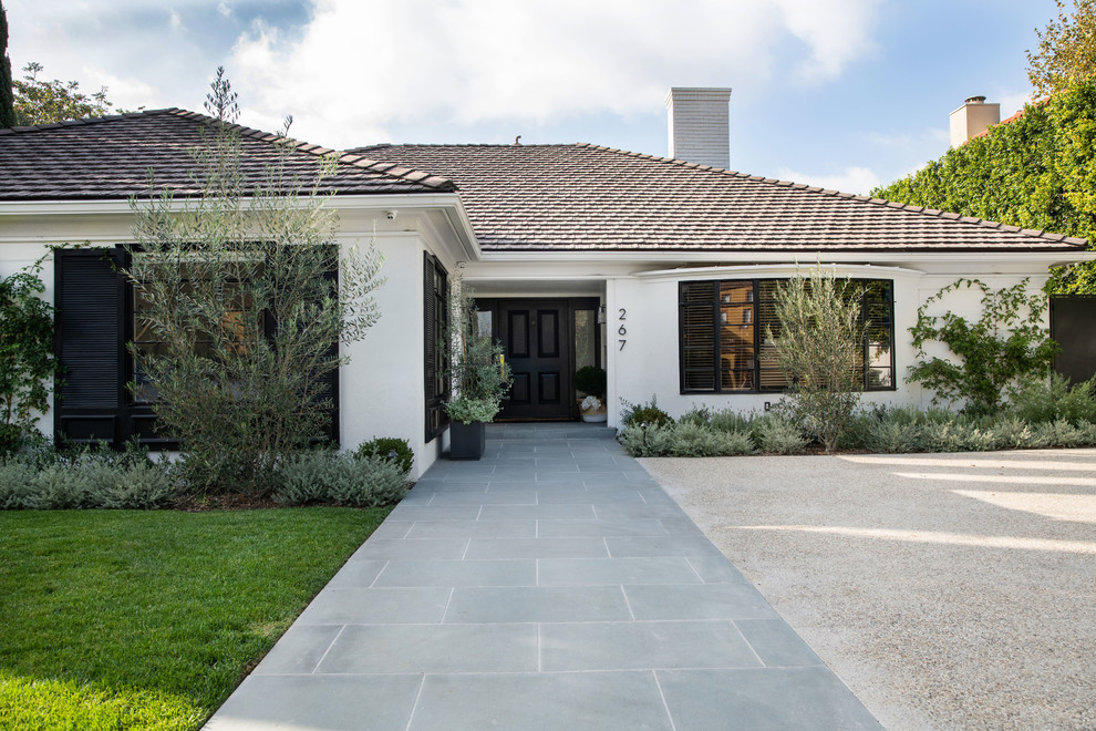 This is an example of a large traditional one-storey brick white house exterior in Los Angeles with a hip roof and a tile roof.