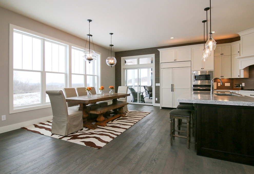 Large transitional u-shaped medium tone wood floor and brown floor eat-in kitchen photo with a drop-in sink, recessed-panel cabinets, white cabinets, marble countertops, beige backsplash, stone tile backsplash, stainless steel appliances and an island