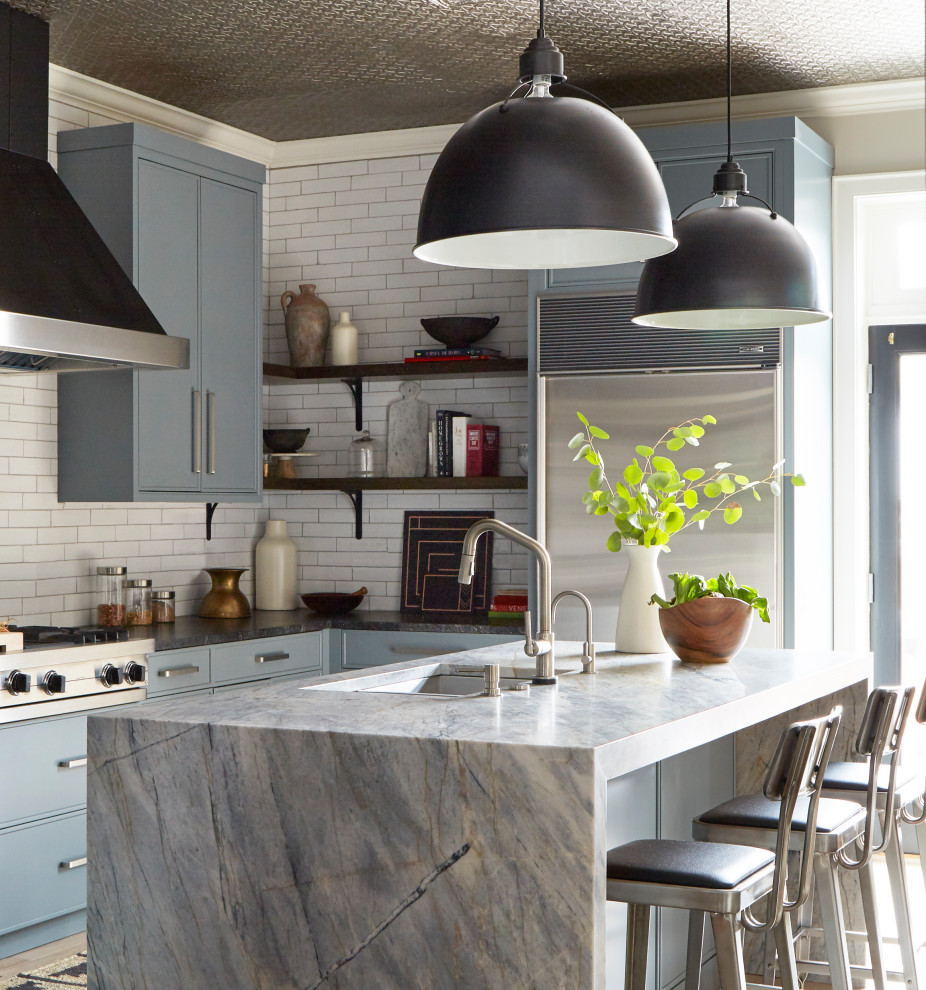 Inspiration for a contemporary u-shaped kitchen in Chicago with an undermount sink, flat-panel cabinets, blue cabinets, white splashback, subway tile splashback, light hardwood floors and with island.