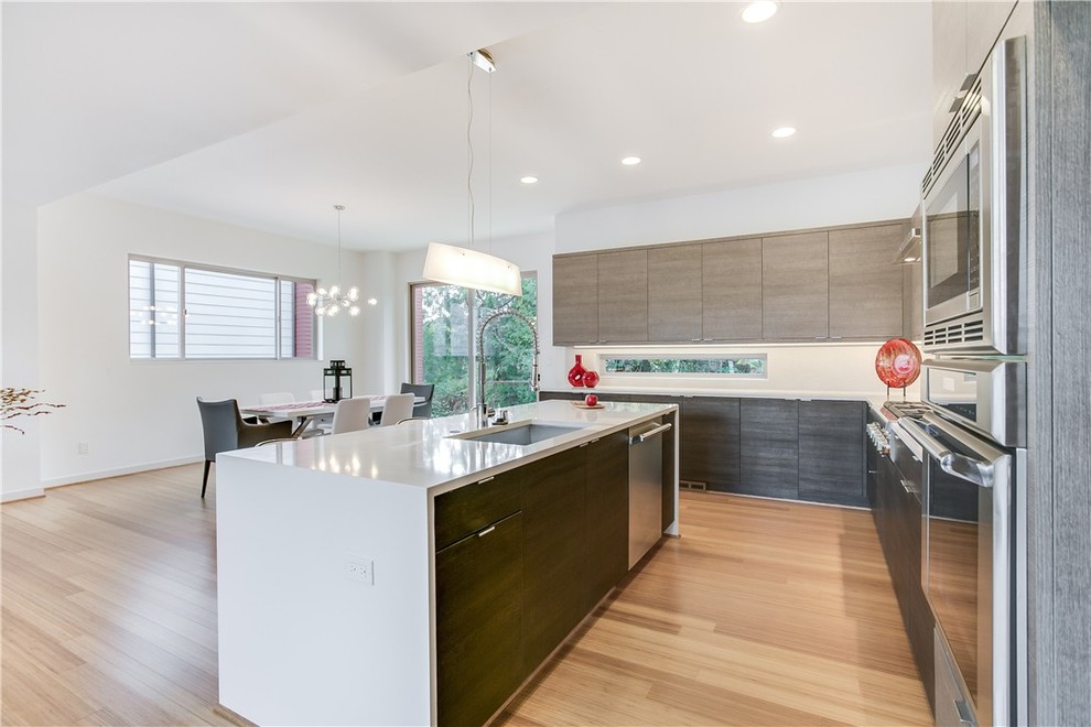 This is an example of a modern l-shaped open plan kitchen in Seattle with flat-panel cabinets, stainless steel appliances and with island.
