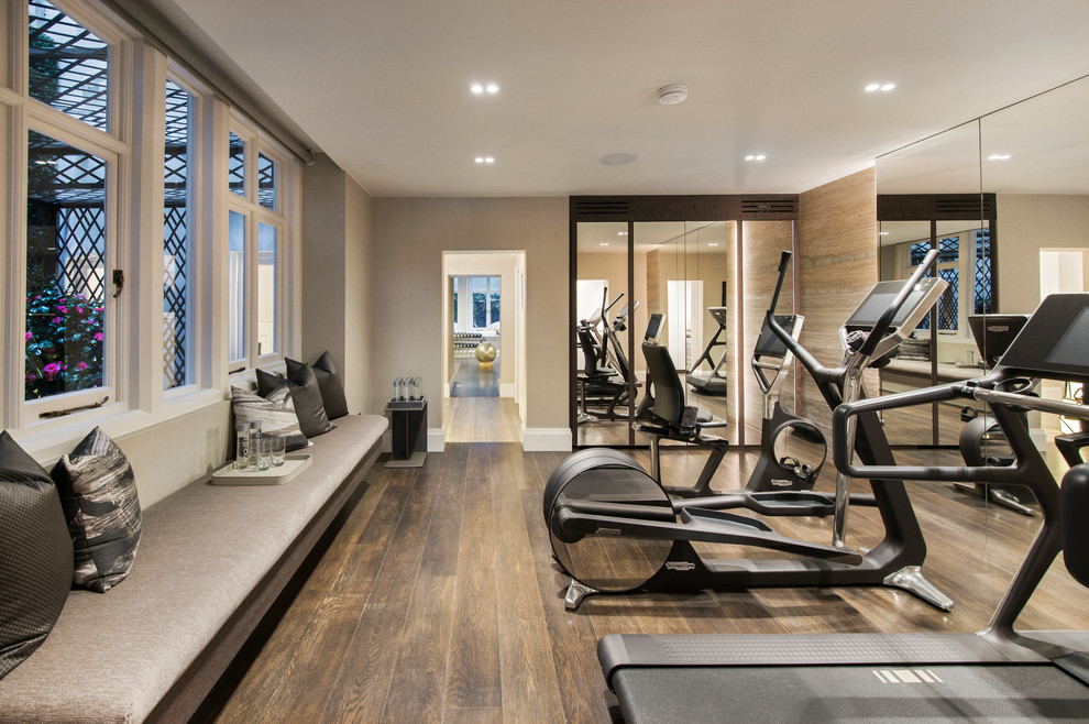 Photo of a mid-sized contemporary multipurpose gym in London with grey walls, dark hardwood floors and brown floor.
