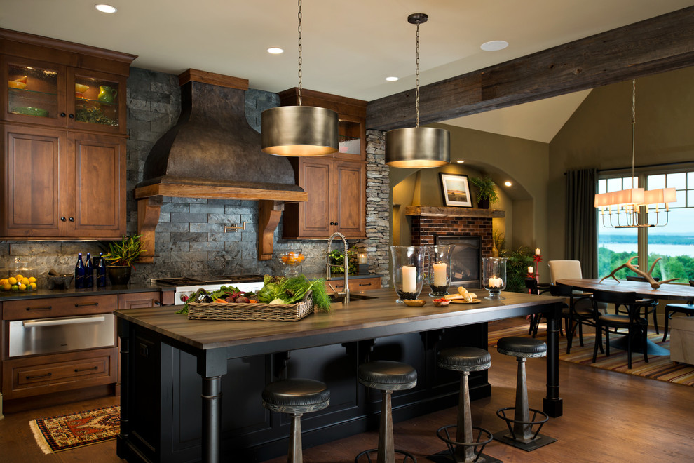 Inspiration for a country eat-in kitchen in New York with raised-panel cabinets, dark wood cabinets, black splashback, stainless steel appliances, dark hardwood floors, with island and slate splashback.