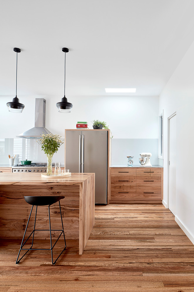 Inspiration for a mid-sized modern u-shaped open plan kitchen in Melbourne with a double-bowl sink, shaker cabinets, light wood cabinets, stainless steel benchtops, metallic splashback, glass sheet splashback, stainless steel appliances, light hardwood floors, with island, brown floor and coffered.