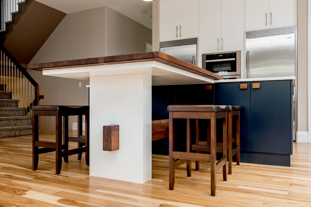 Kitchen pantry - large transitional l-shaped light wood floor and beige floor kitchen pantry idea with a double-bowl sink, flat-panel cabinets, white cabinets, quartz countertops, gray backsplash, cement tile backsplash, stainless steel appliances, an island and white countertops
