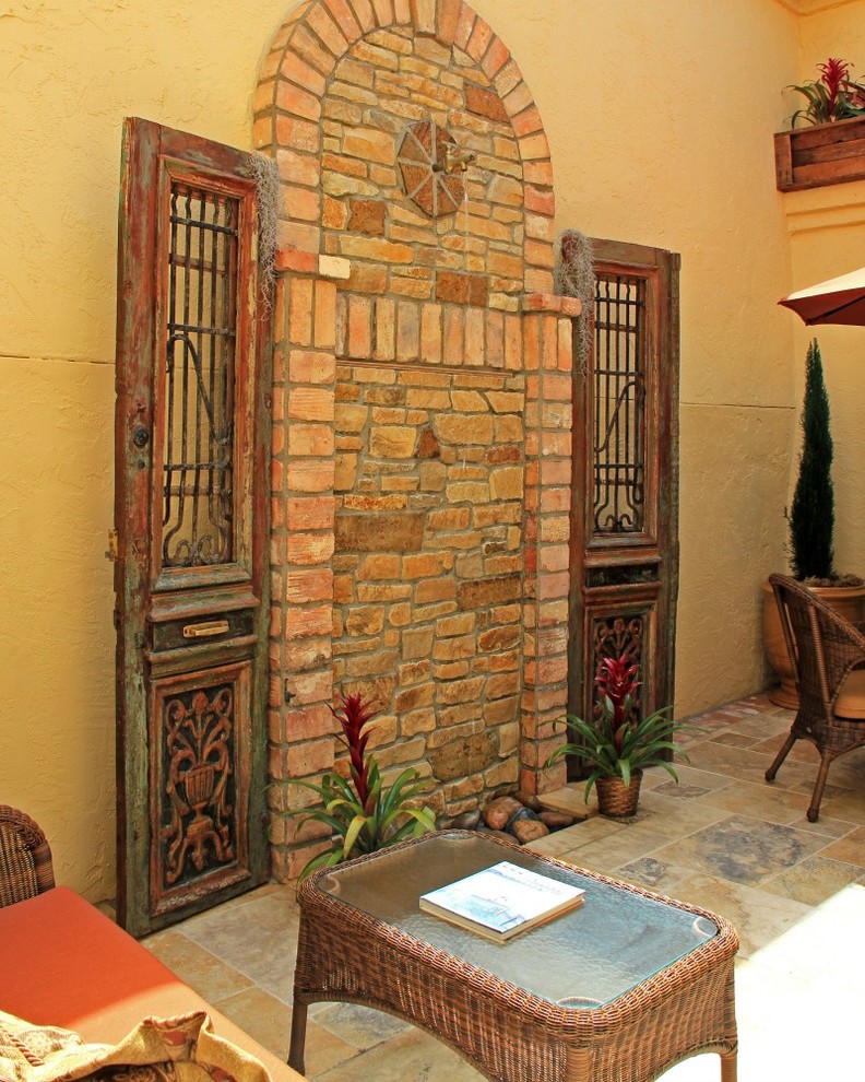 This is an example of a small mediterranean courtyard patio in San Diego with a water feature, tile and no cover.