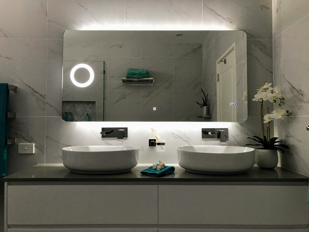 Immagine di una stanza da bagno con doccia design di medie dimensioni con ante bianche, piastrelle bianche, piastrelle in gres porcellanato, top in quarzo composito, top grigio, due lavabi e mobile bagno sospeso