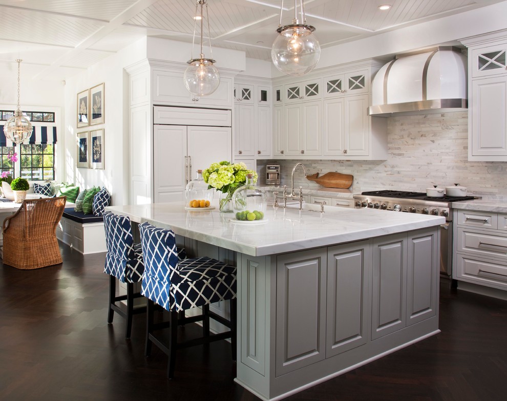 Design ideas for a large beach style l-shaped eat-in kitchen in San Diego with white cabinets, marble benchtops, white splashback, dark hardwood floors, with island, raised-panel cabinets and stainless steel appliances.