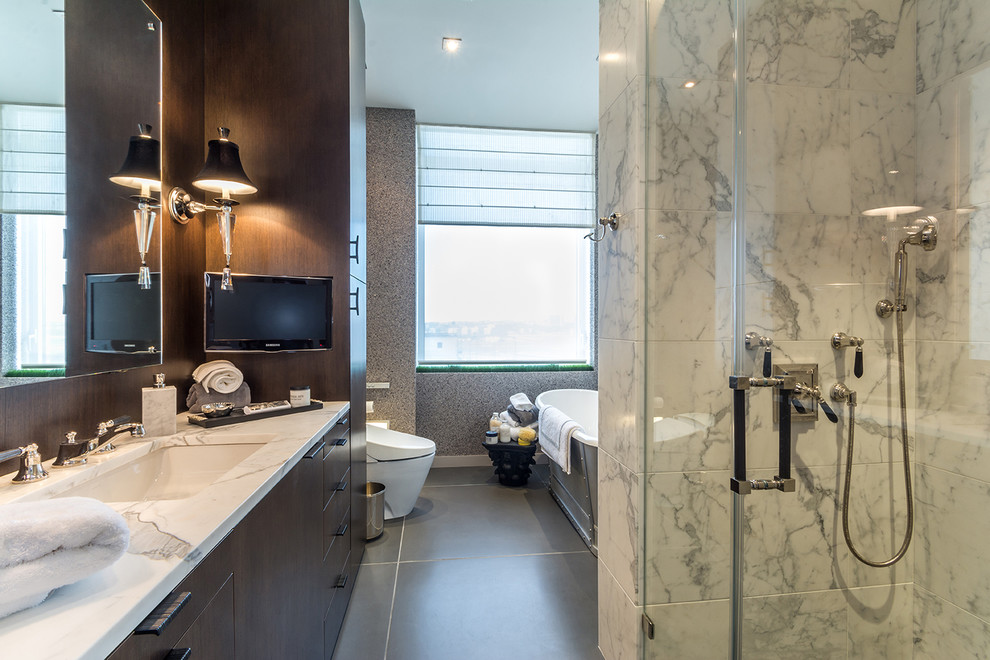 Mid-sized transitional master bathroom in New York with an undermount sink, flat-panel cabinets, dark wood cabinets, marble benchtops, a freestanding tub, an alcove shower, a one-piece toilet, black and white tile, stone slab, concrete floors, multi-coloured walls, grey floor and a hinged shower door.