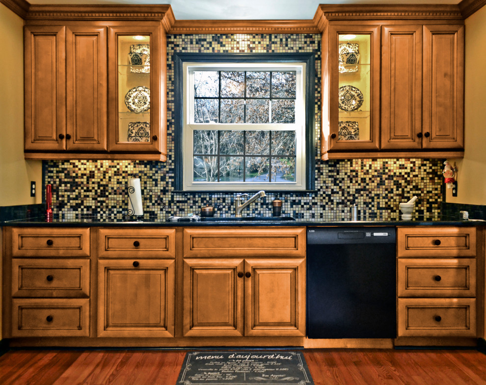 Mid-sized traditional single-wall eat-in kitchen in Toronto with a double-bowl sink, raised-panel cabinets, medium wood cabinets, multi-coloured splashback, mosaic tile splashback, black appliances, medium hardwood floors, granite benchtops, no island and brown floor.