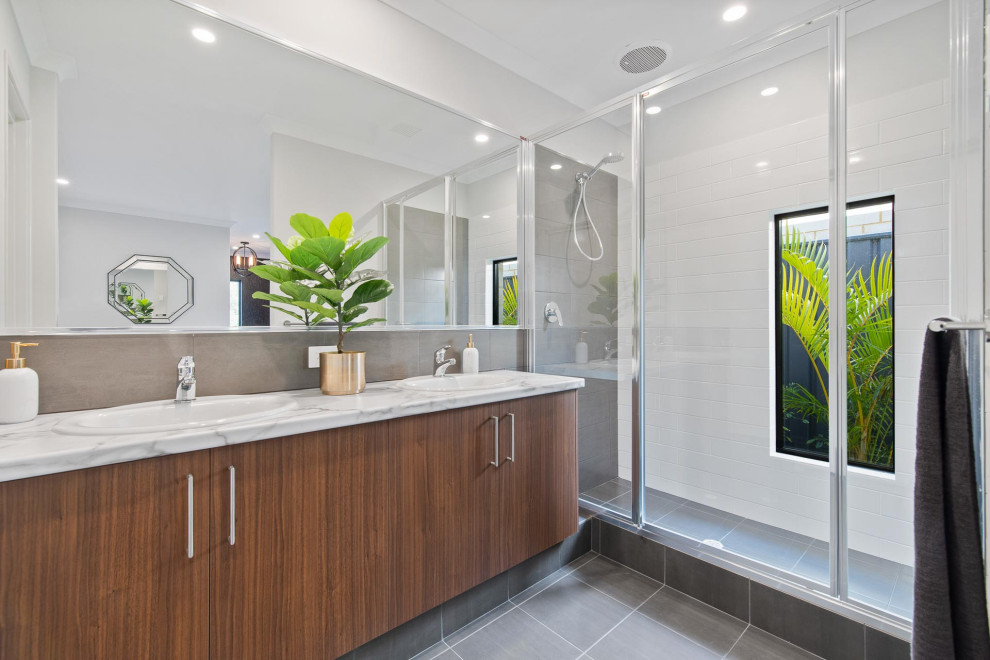 Inspiration for a contemporary bathroom in Perth with flat-panel cabinets, medium wood cabinets, an alcove shower, white tile, an undermount sink, grey floor, a hinged shower door, white benchtops and a double vanity.
