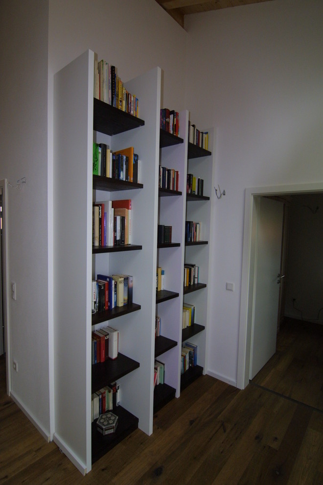 Mittelgroßes Modernes Lesezimmer mit weißer Wandfarbe, dunklem Holzboden, freistehendem Schreibtisch und braunem Boden in Sonstige