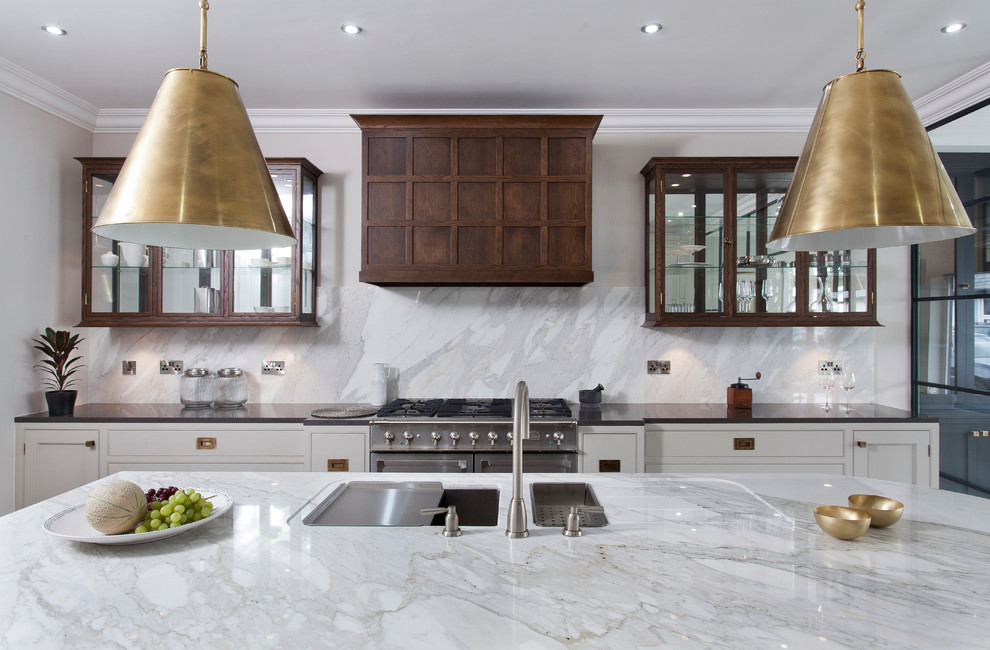 This is an example of a contemporary galley kitchen in Dublin with an undermount sink, beaded inset cabinets, marble benchtops, stainless steel appliances, light hardwood floors and with island.