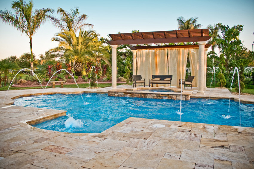 Design ideas for a large tropical backyard custom-shaped pool in Miami with a hot tub and natural stone pavers.