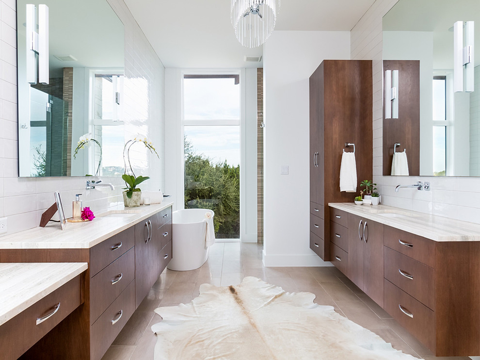 Photo of a contemporary master bathroom in Austin with flat-panel cabinets, medium wood cabinets, a freestanding tub, white tile, white walls, an undermount sink and beige floor.
