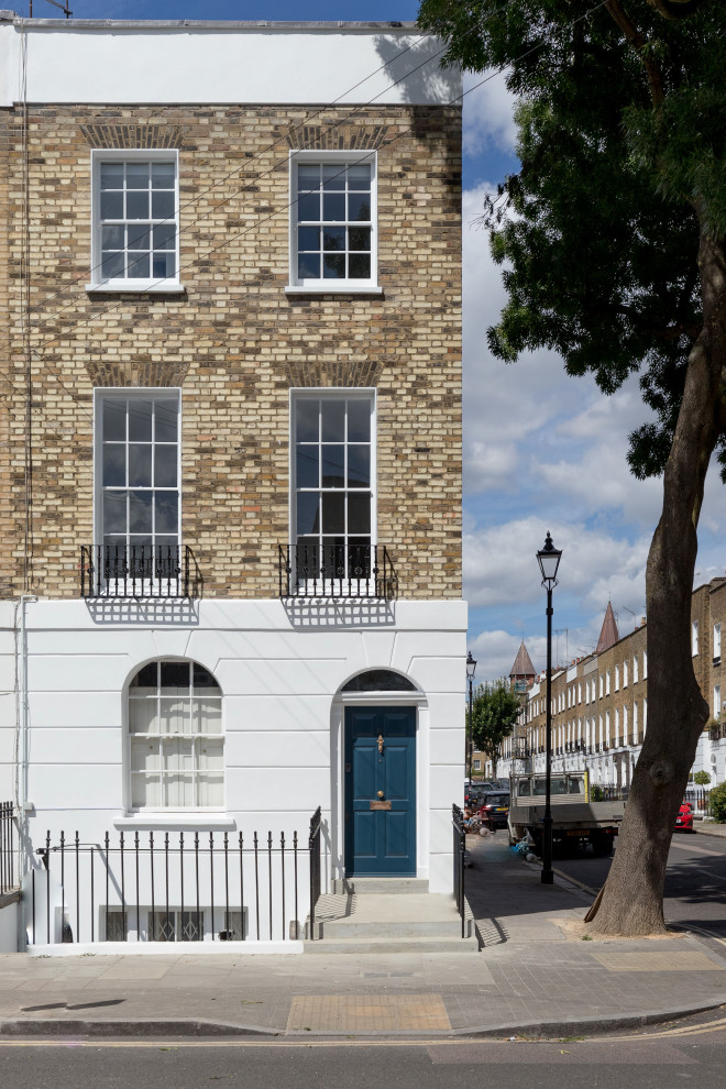 Inspiration for a mid-sized traditional three-storey brick beige townhouse exterior in London with a butterfly roof, a tile roof and a black roof.