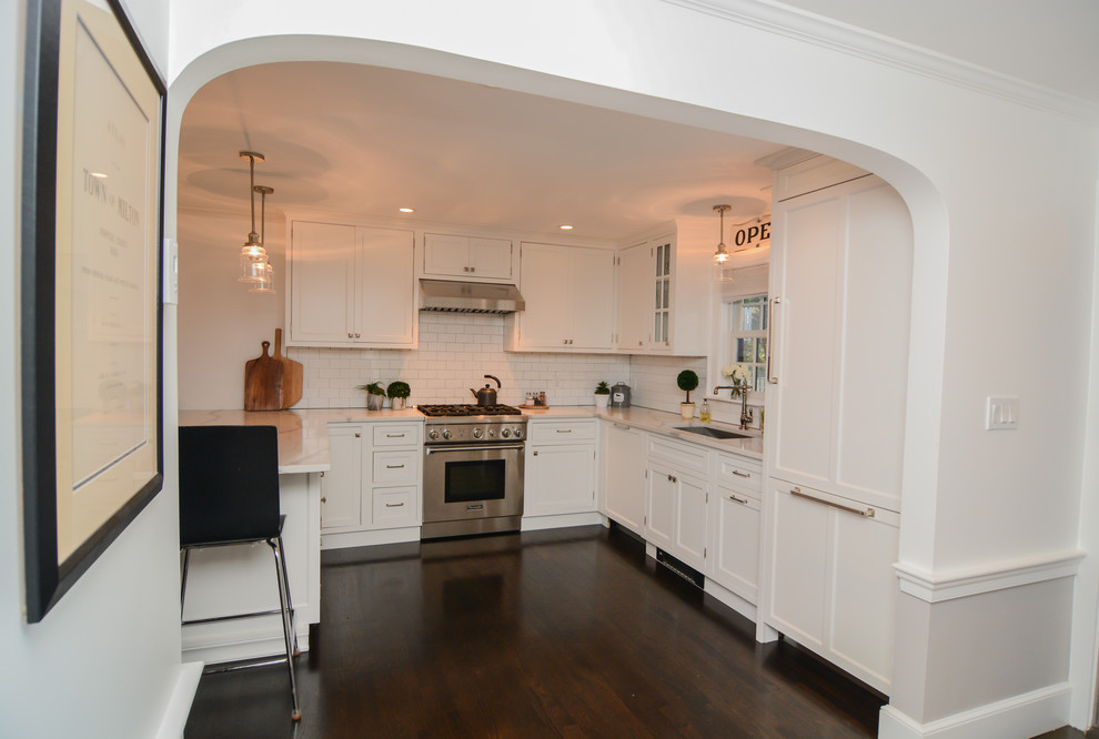 Photo of a mid-sized contemporary u-shaped eat-in kitchen in Boston with a single-bowl sink, shaker cabinets, white cabinets, marble benchtops, white splashback, subway tile splashback, stainless steel appliances, dark hardwood floors, a peninsula and black floor.
