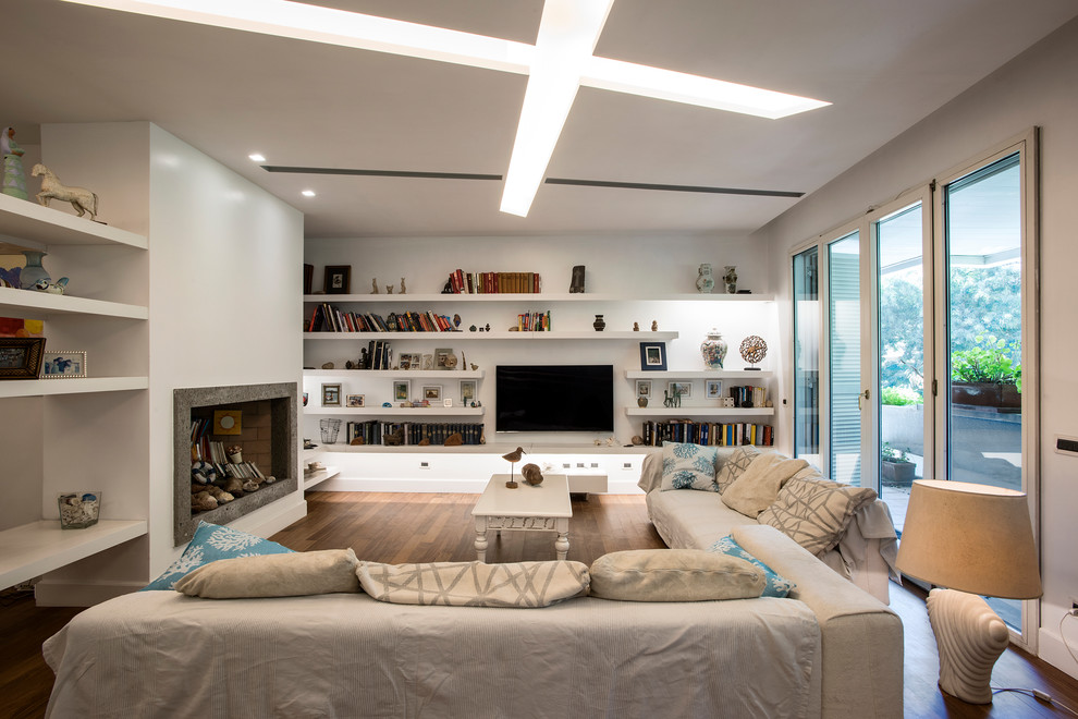 Photo of a large contemporary open concept family room in Rome with a library, white walls, medium hardwood floors, a standard fireplace, a stone fireplace surround, a wall-mounted tv and brown floor.