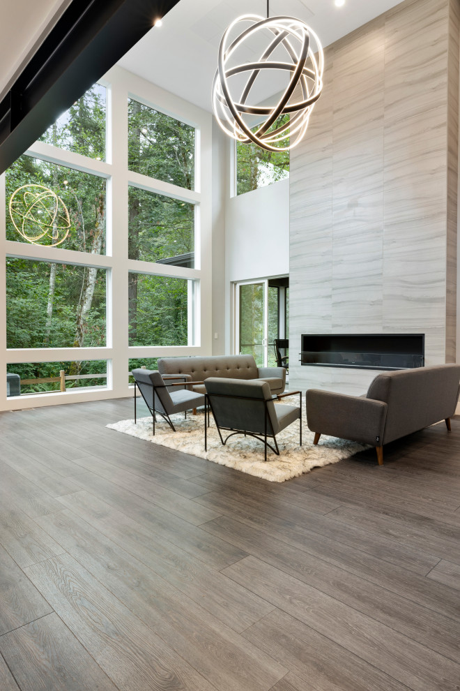 Inspiration pour un grand salon minimaliste ouvert avec une salle de réception, un mur gris, un sol en vinyl, une cheminée standard, un manteau de cheminée en pierre, un sol gris et un plafond voûté.